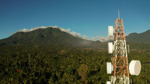 Telecommunication tower, communication antenna against mountains and rainforest, aerial view. 