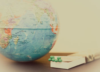 Close-up of globe and matchsticks against white background on table