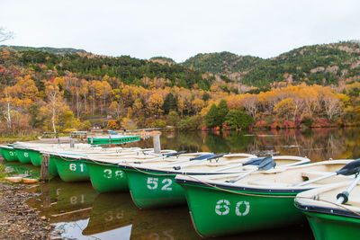 Boats moored in lake against sky during autumn