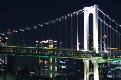 Illuminated bridge over river in city at night