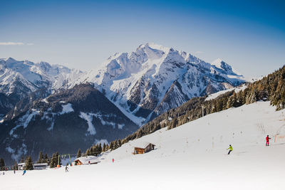 Distant view of people skiing on snowcapped mountain