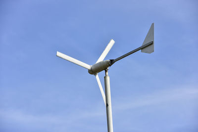 Low angle view of wind turbine against blue sky