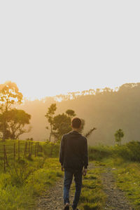 Rear view of man standing on field against sky