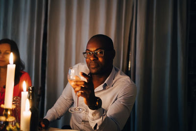 Portrait of mature man having drink while sitting with friend at dinner party