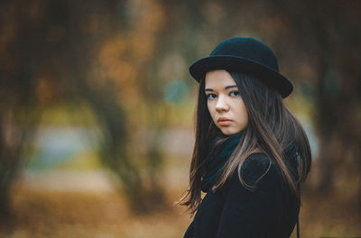 Portrait of young woman wearing hat standing outdoors