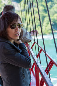 Portrait of young woman standing by railing