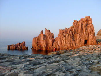 Rock formations in sea against clear sky