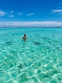 Woman in sea against blue sky