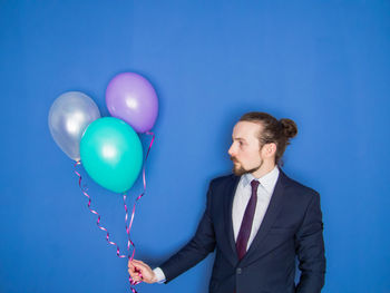 Portrait of a smiling young man holding blue balloons