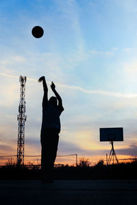 Silhouette man playing basketball against sky during sunset