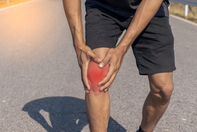 Low section of man holding hands on road