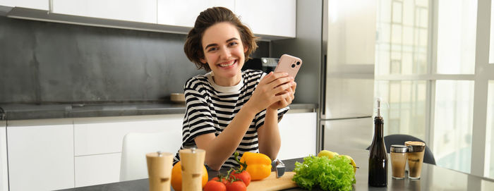 Young woman using mobile phone while sitting in bathroom