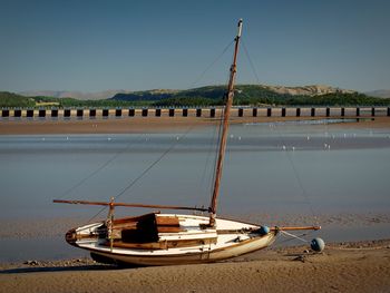 Sailboats moored on beach against clear sky