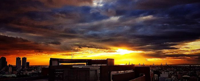 Cityscape against dramatic sky during sunset