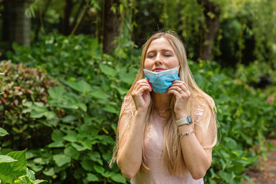 Close-up of woman wearing mask against plants outdoors