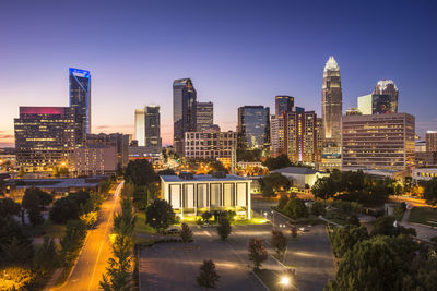 Illuminated buildings in city against clear sky