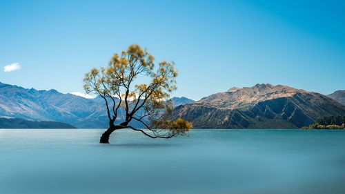 Scenic view of lake by mountains against blue sky