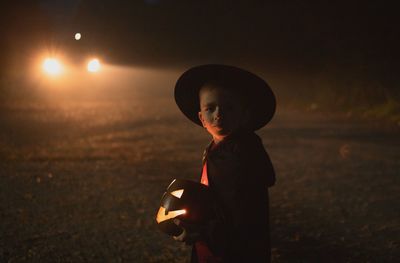 Side view of boy standing against illumination