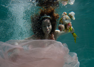 Woman holding flowers while swimming in pool