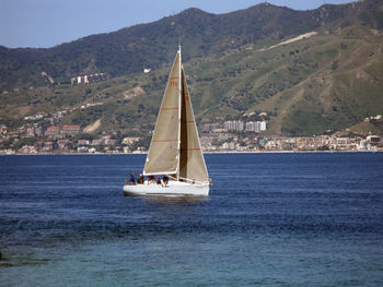 Sailboat sailing on sea against mountains