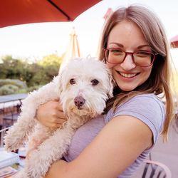 Portrait of smiling woman carrying dog outdoors