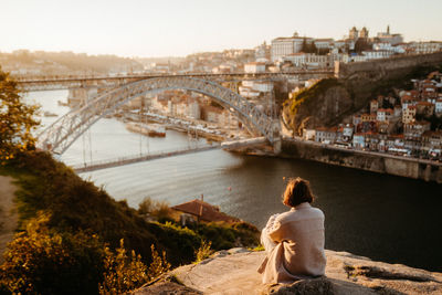 Rear view of woman sitting on bridge