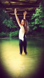 Full length portrait of young woman jumping in water