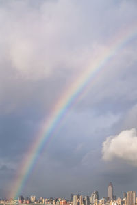 Rainbow over city against sky