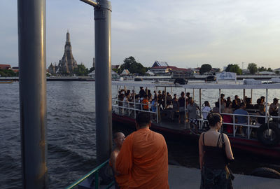 Passengers traveling in ferry against sky during sunset