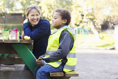 Happy teacher looking at boy in reflective jacket