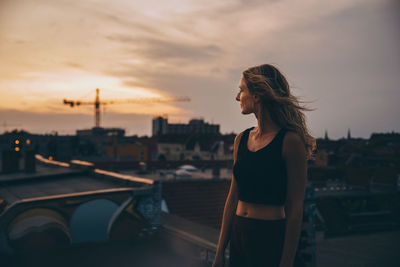 Thoughtful woman looking away while standing on terrace during party against sky