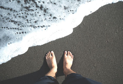Low section of man standing on beach