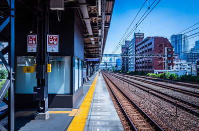 Train at railroad station in city against sky