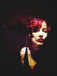 Portrait of young woman looking away against black background