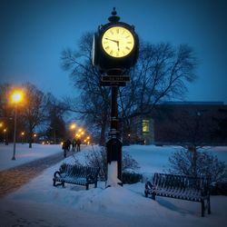 Illuminated street light on snow covered landscape at night