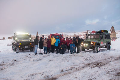 People on snow field against sky during winter