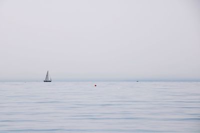 Sailboat in sea against clear sky