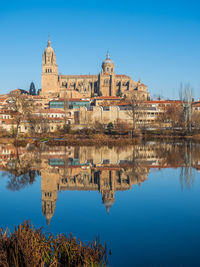 Reflection of building in water against clear blue sky