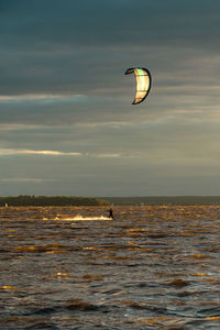 Person paragliding in sea against sky