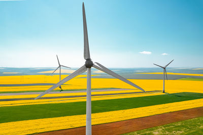 Aerial view of wind turbines farm on agricultural field in summer