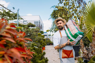 Man gardener holding a box of flowers. e-commerce, online order concept.