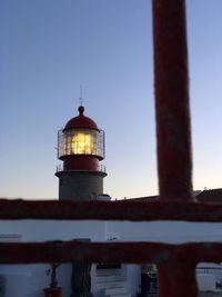 Low angle view of lighthouse by building against clear sky