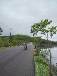 People riding motorcycle on road against sky