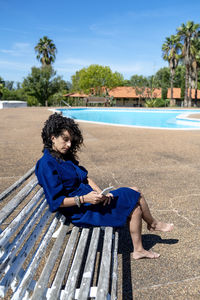 Portrait of woman sitting on bench at park