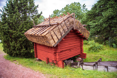 Wooden house on field by trees