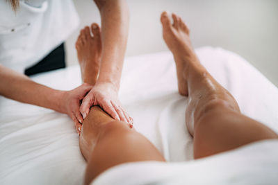 Midsection of massage therapist massaging female customer leg in spa