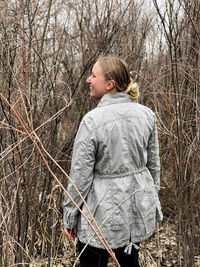 Side view of woman standing against tall grass