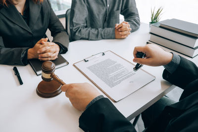 Midsection of man holding paper while sitting on table