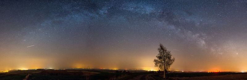 Panoramic view of landscape against star field in sky at night
