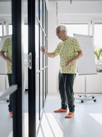 Senior entrepreneur writing in glass wall while standing at office